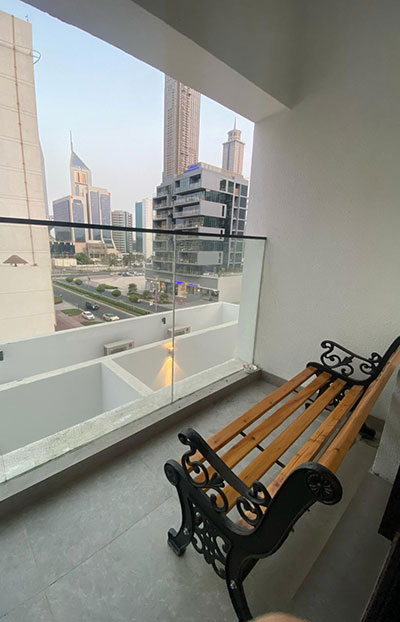 Balcony with wooden bench and city view at urban panda hostels DWTC