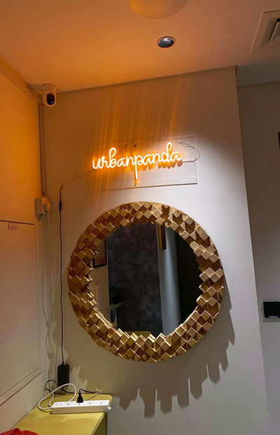 Neon Urban Panda sign and geometric mirror at hostel